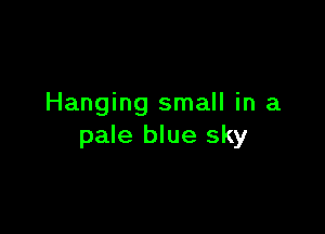 Hanging small in a

pale blue sky